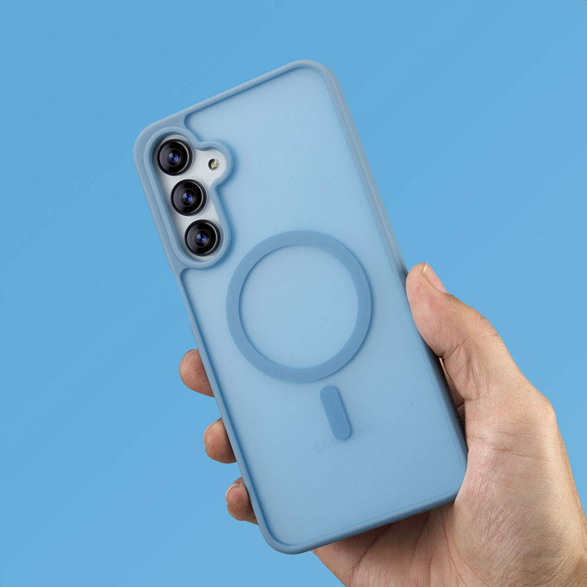 Una mano che tiene una custodia per telefono azzurra con un cerchio e un rettangolo sul retro, con tre lenti della fotocamera. Sfondo blu.