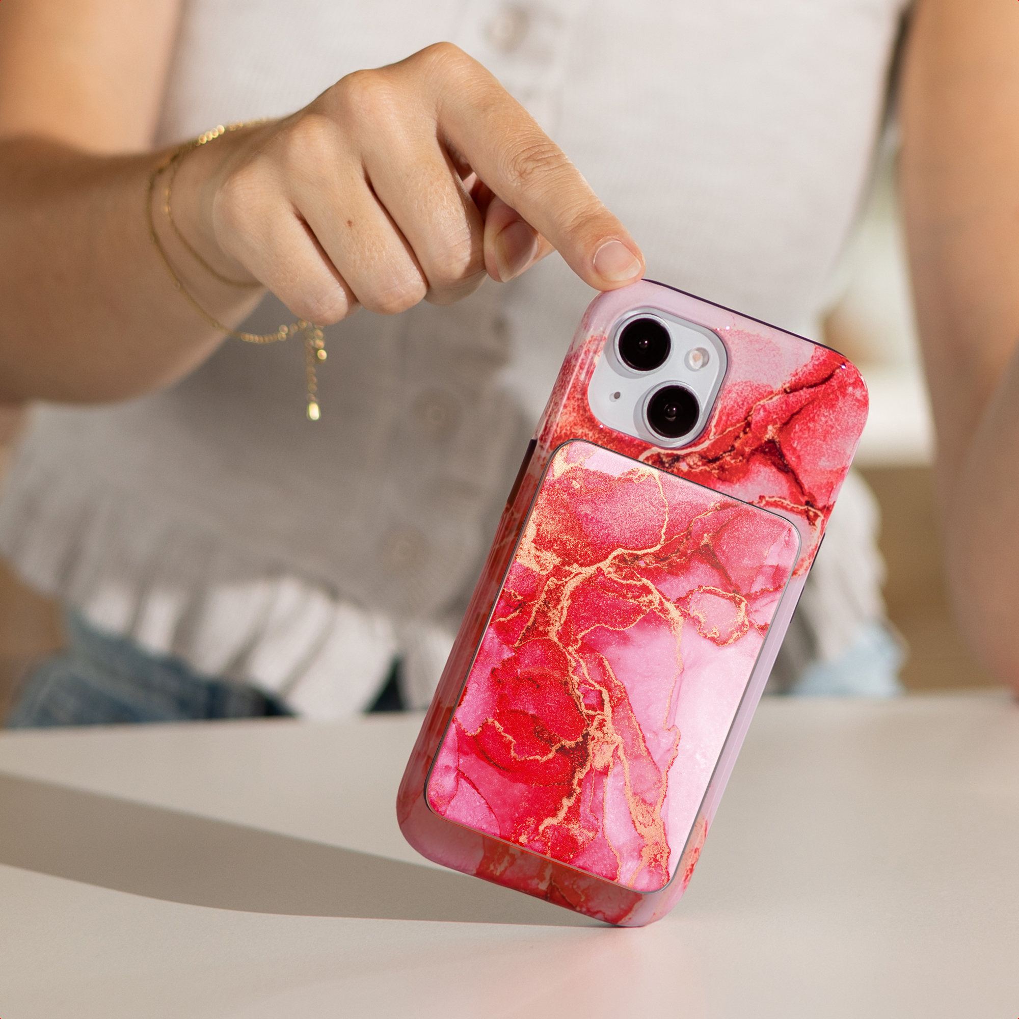 Een hand houdt een telefoon vast met een rood en goud marmerontwerp. De telefoon staat scherp, tegen een vage achtergrond.