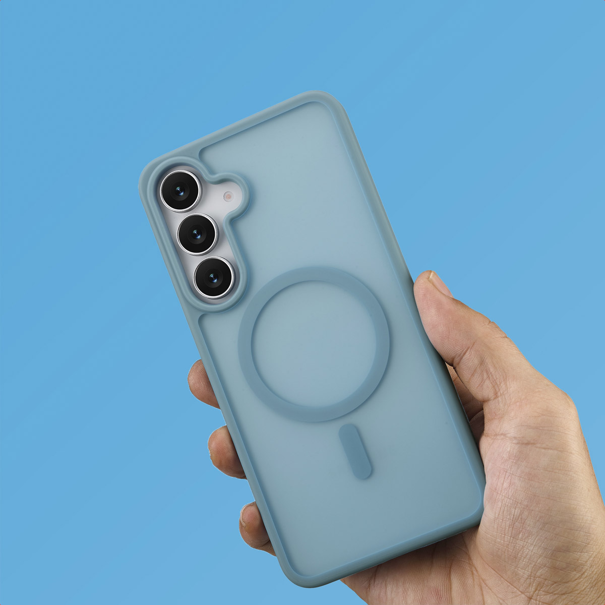 Hand houdt een lichtblauwe telefoonhoes vast met drie cameralenzen. De achtergrond is effen blauw.