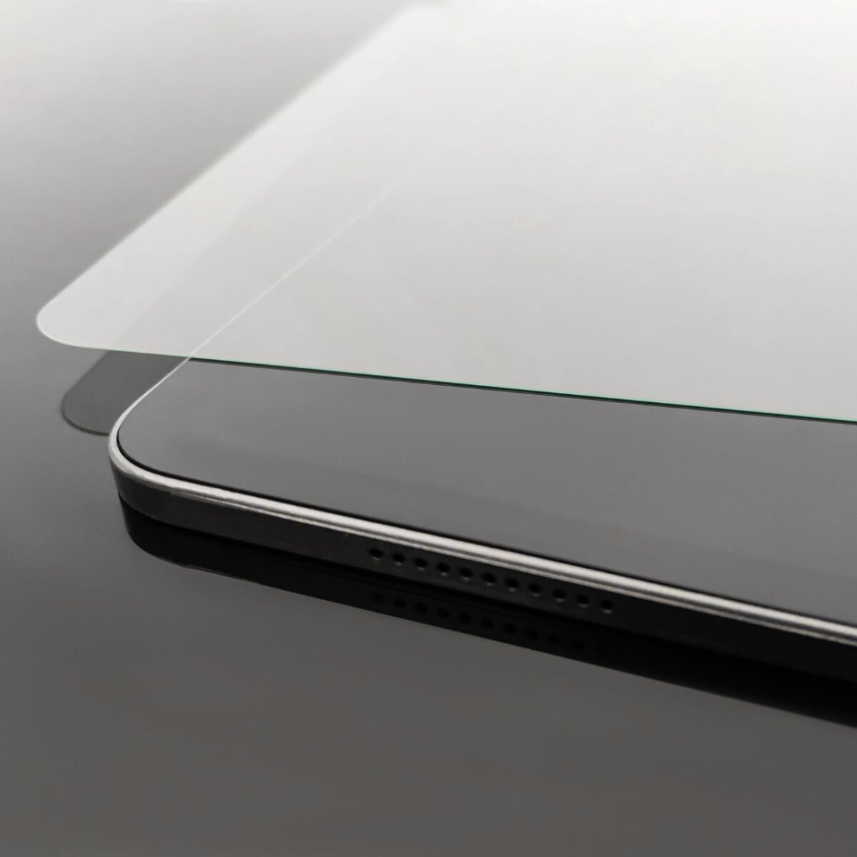 Primo piano di un tablet. Lo schermo è bianco, con un bordo nero. La superficie lucida riflette il tablet.