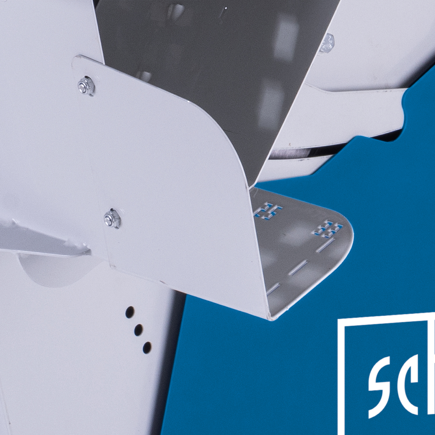 Close-up of a white, metallic structure with bolts and a gray element. The background is blue with a white logo in the corner.
