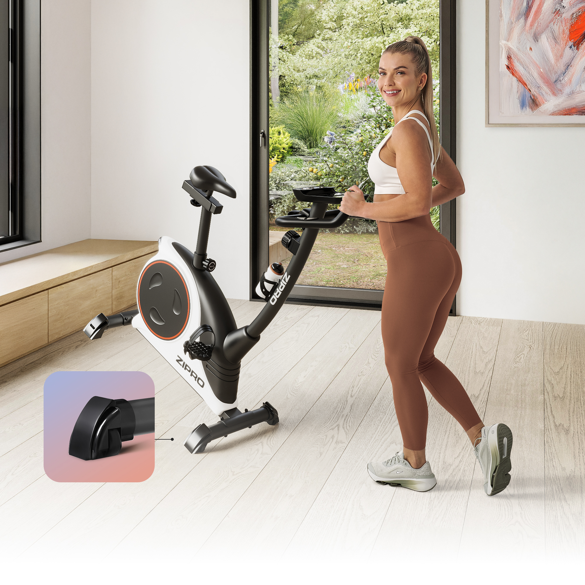 Eine Frau steht neben einem Trainingsfahrrad. Sie lächelt, trägt ein weißes Oberteil und braune Leggings. Durch das Fenster sieht man einen Garten.