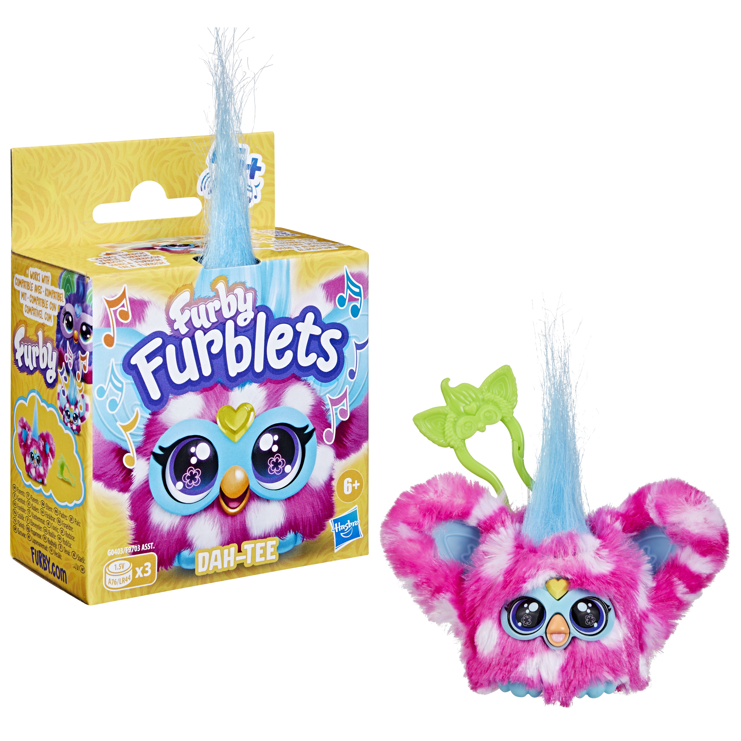 Se muestra un juguete Furblets y su caja. El juguete es rosa y blanco. Tiene pelo azul y un accesorio verde.