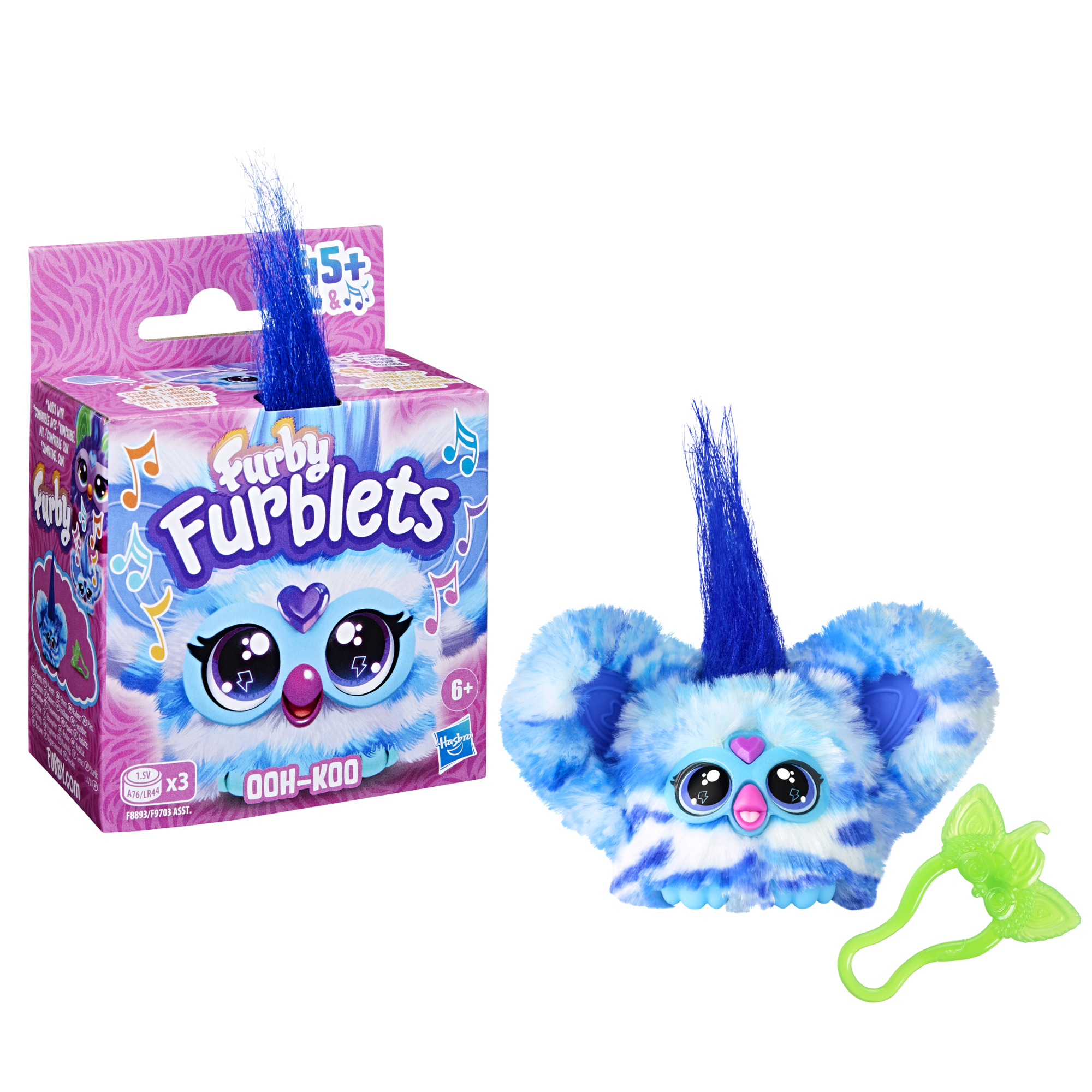 Un juguete Furby Furblets y su caja. El Furby es azul y blanco con un mechón de pelo azul. La caja es rosa y morada.