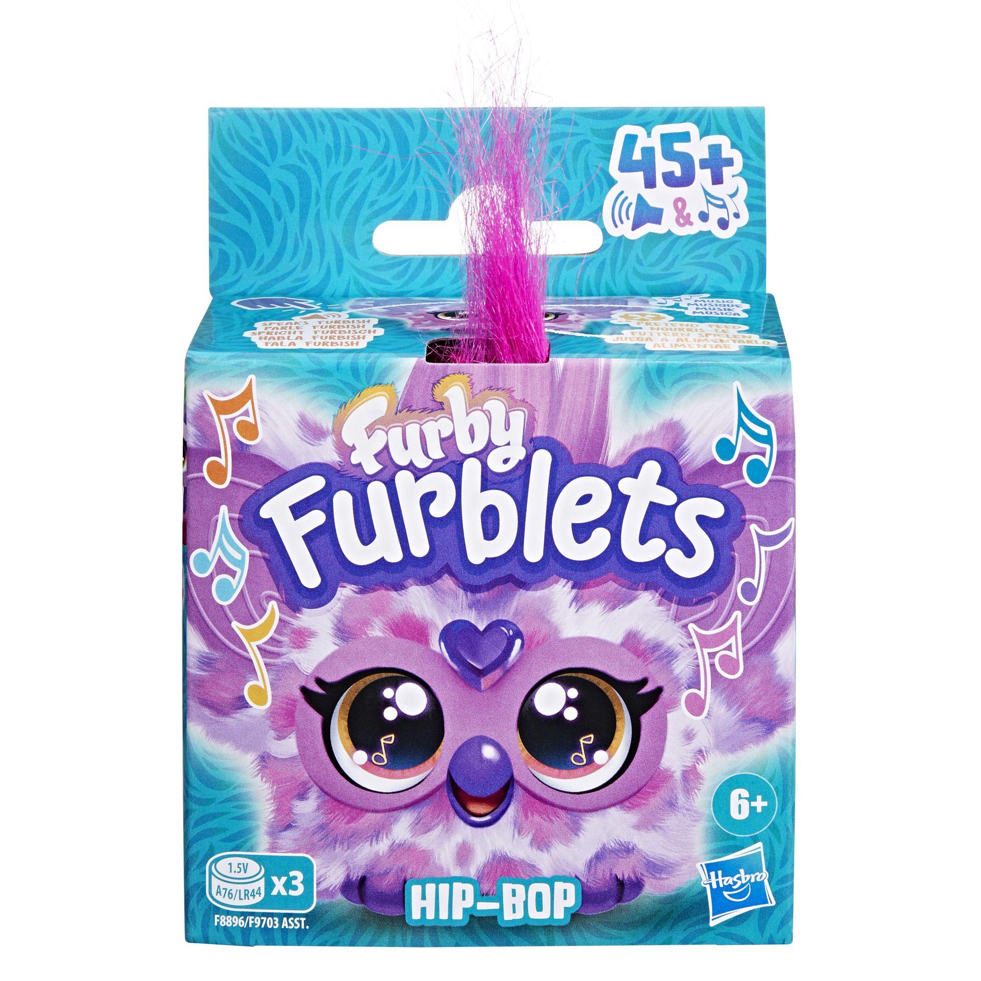 Una caja de Furby Furblets. Presenta una cara de Furby morada, texto, notas musicales y un mechón de pelo rosa.