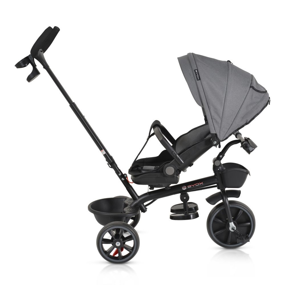 Un triciclo gris y negro con capota. Tiene tres ruedas, asiento, cesta y un mango largo para dirigir.