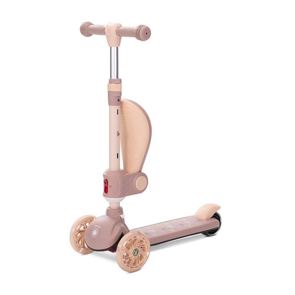 Un patinete rosa y beige de tres ruedas. Tiene manillar, plataforma para los pies con estrellas y un protector beige.