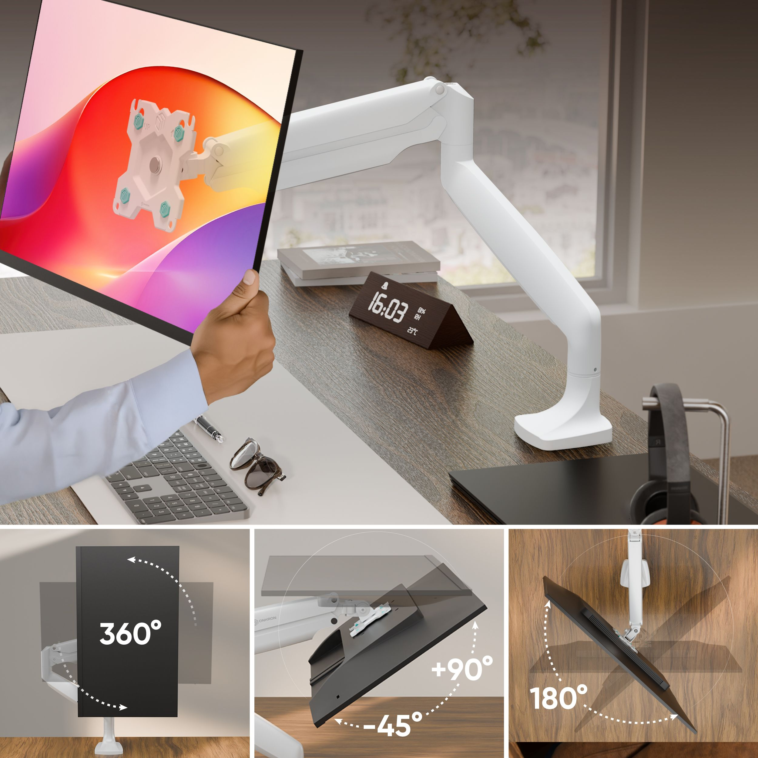 Mężczyzna trzyma monitor z kolorowym wyświetlaczem. Monitor zamontowany na białym ramieniu. Biurko z klawiaturą, okularami i zegarem.