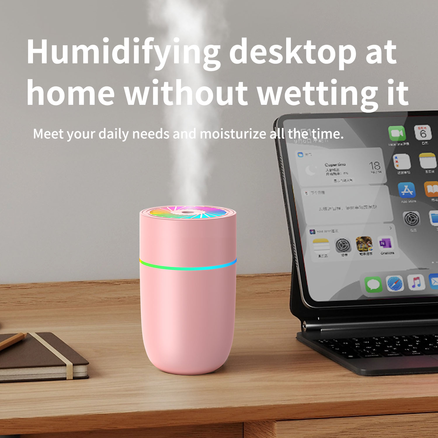 Ein rosa Luftbefeuchter mit bunten Lichtern steht auf einem Holzschreibtisch. Ein Tablet und ein Notizbuch sind ebenfalls zu sehen.