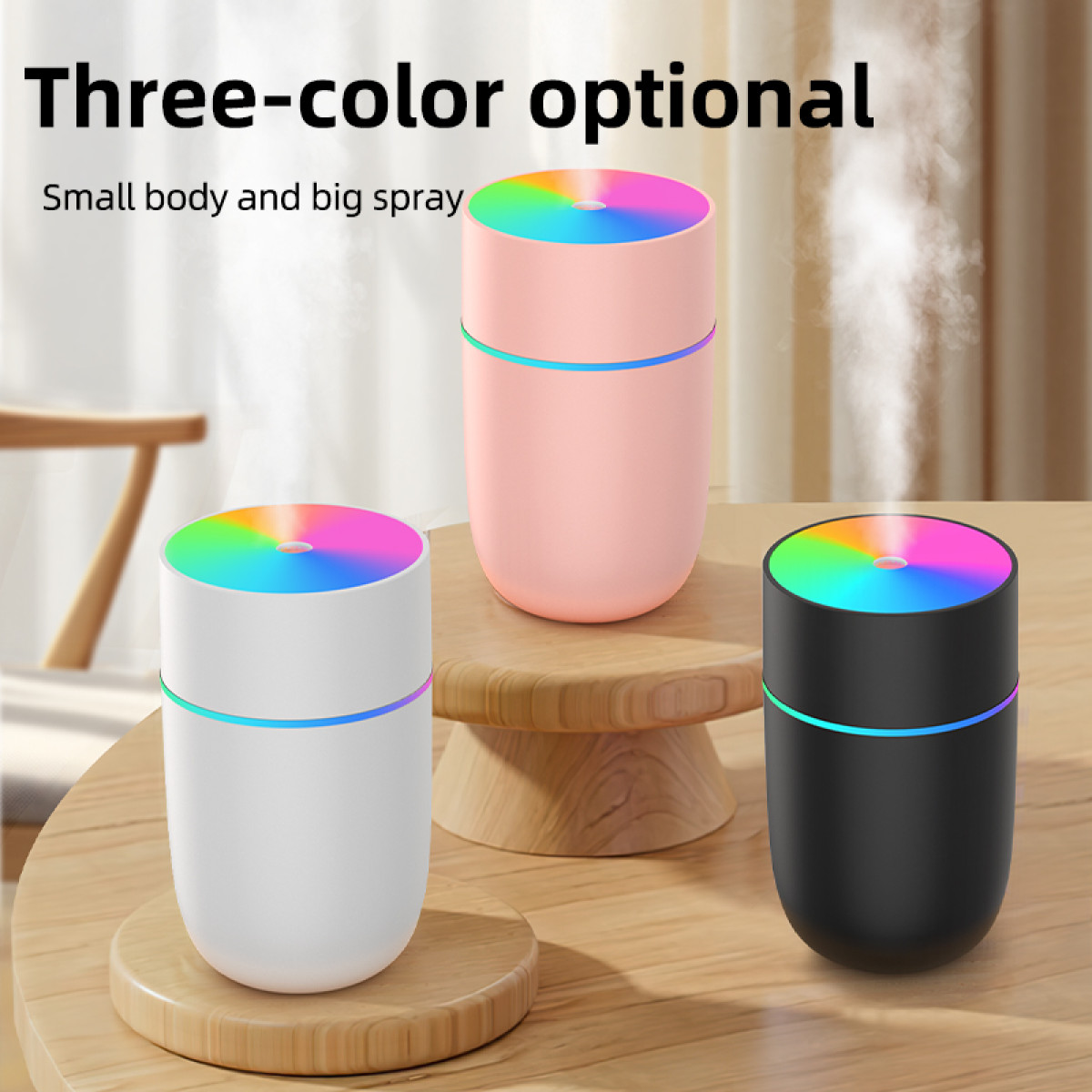 Drei Luftbefeuchter in Weiß, Rosa und Schwarz mit Regenbogen-Oberteilen. Der Text lautet 'Drei-Farben-optional' und 'Kleiner Körper und großer Sprühstoß'.