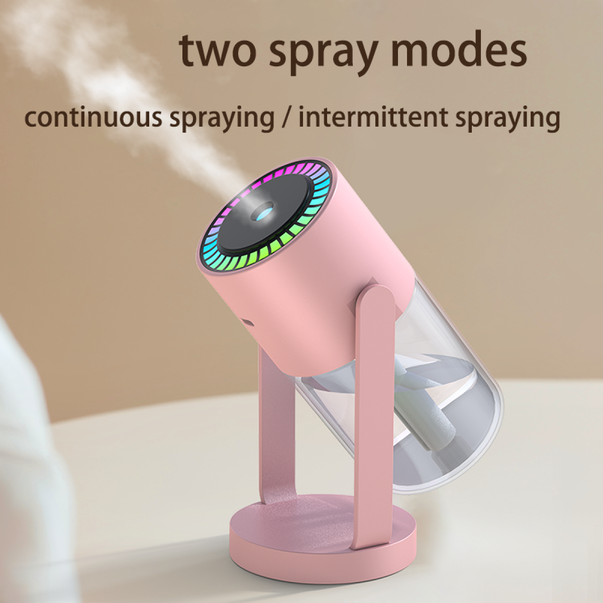 Ein rosa Luftbefeuchter mit einem transparenten Wassertank sprüht Nebel. Er hat einen bunten Lichtring und steht auf einem Tisch.