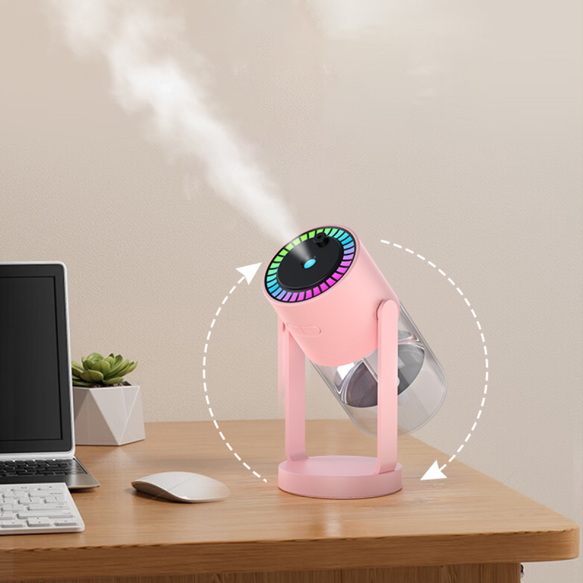 Ein rosa Luftbefeuchter mit farbigem Lichtring, der Dampf abgibt, auf einem Holztisch. Ein Laptop, eine Pflanze und eine Maus sind ebenfalls vorhanden.