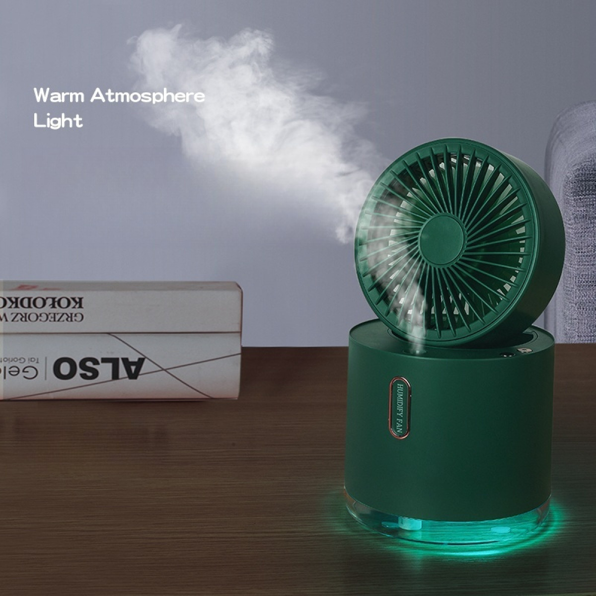 Un ventilador humidificador verde emite vapor. Un libro y una silla gris están en el fondo. El ventilador tiene una base verde con luz.