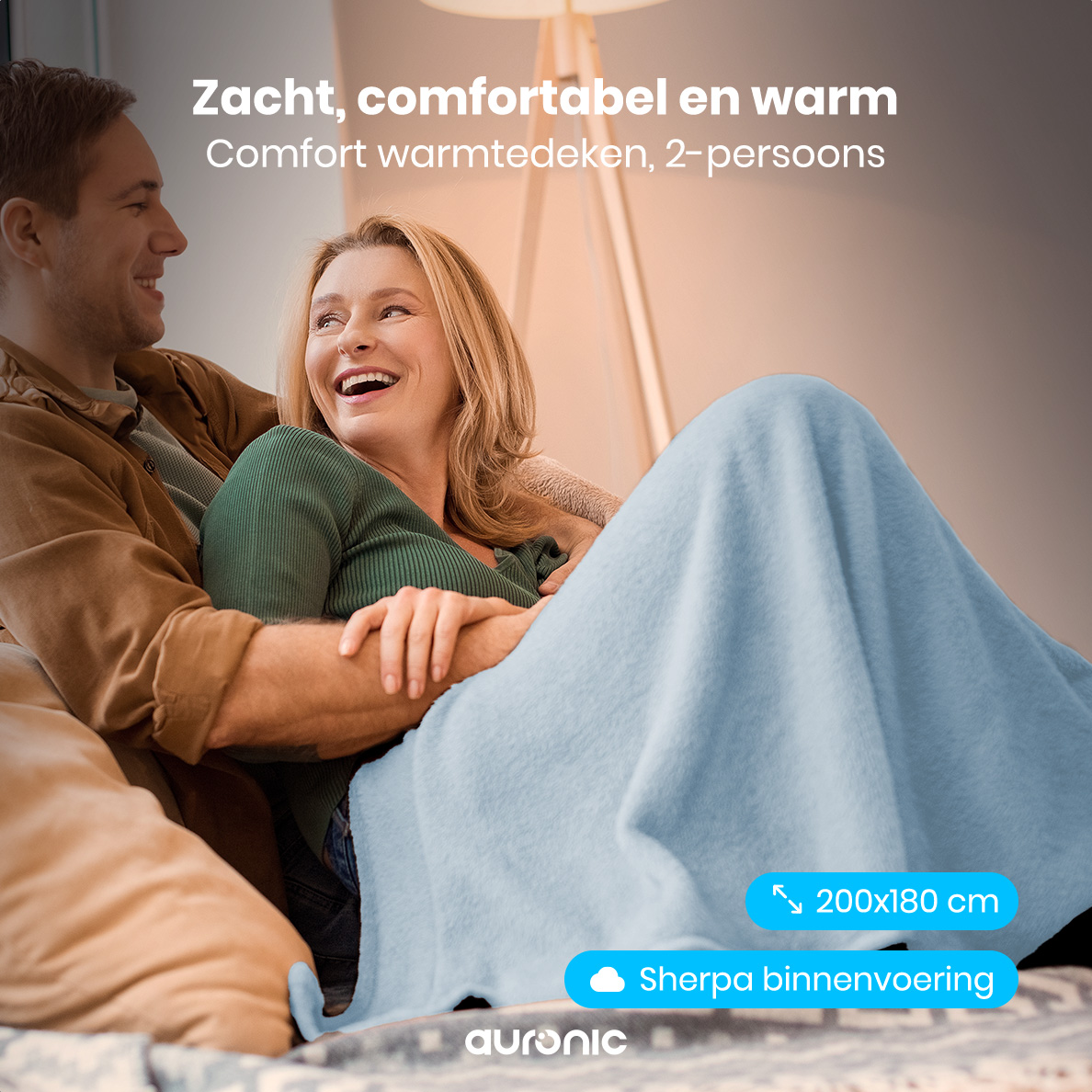 A couple smiles, covered by a light blue blanket. Text overlay reads 'Soft, comfortable and warm'.
