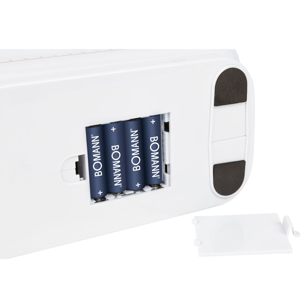 Białe urządzenie z czterema niebieskimi bateriami BOMANN. Drzwiczki komory baterii są otwarte. Czarne podkładki znajdują się na podstawie urządzenia.