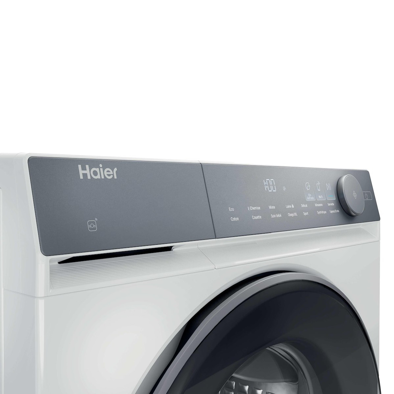 Una lavatrice Haier bianca. Pannello di controllo grigio con display digitale, pulsanti e manopola. L'oblò è nero.