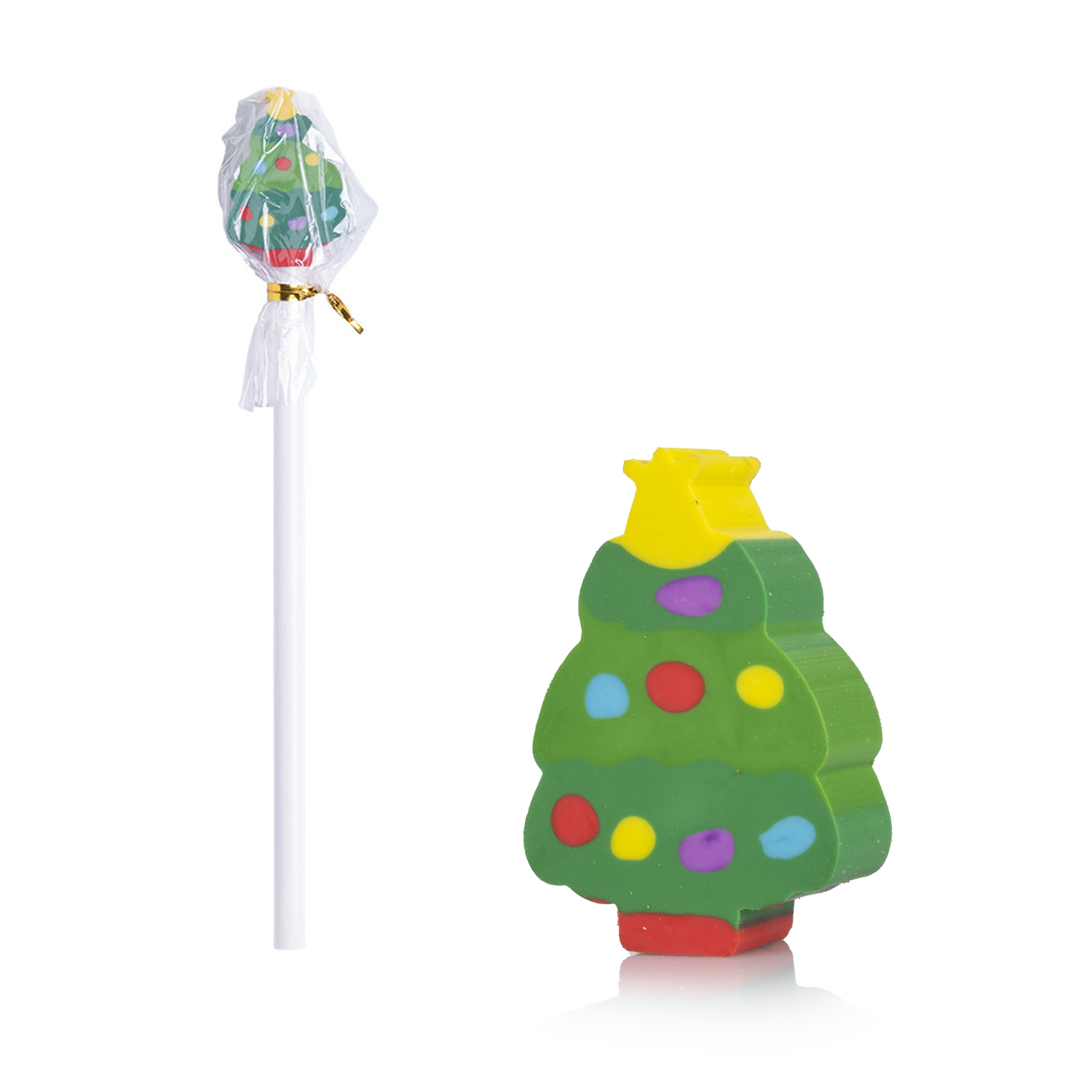 Una piruleta con forma de árbol de Navidad y un borrador con forma de árbol se encuentran sobre una superficie blanca. La piruleta está envuelta. El borrador tiene puntos de colores.