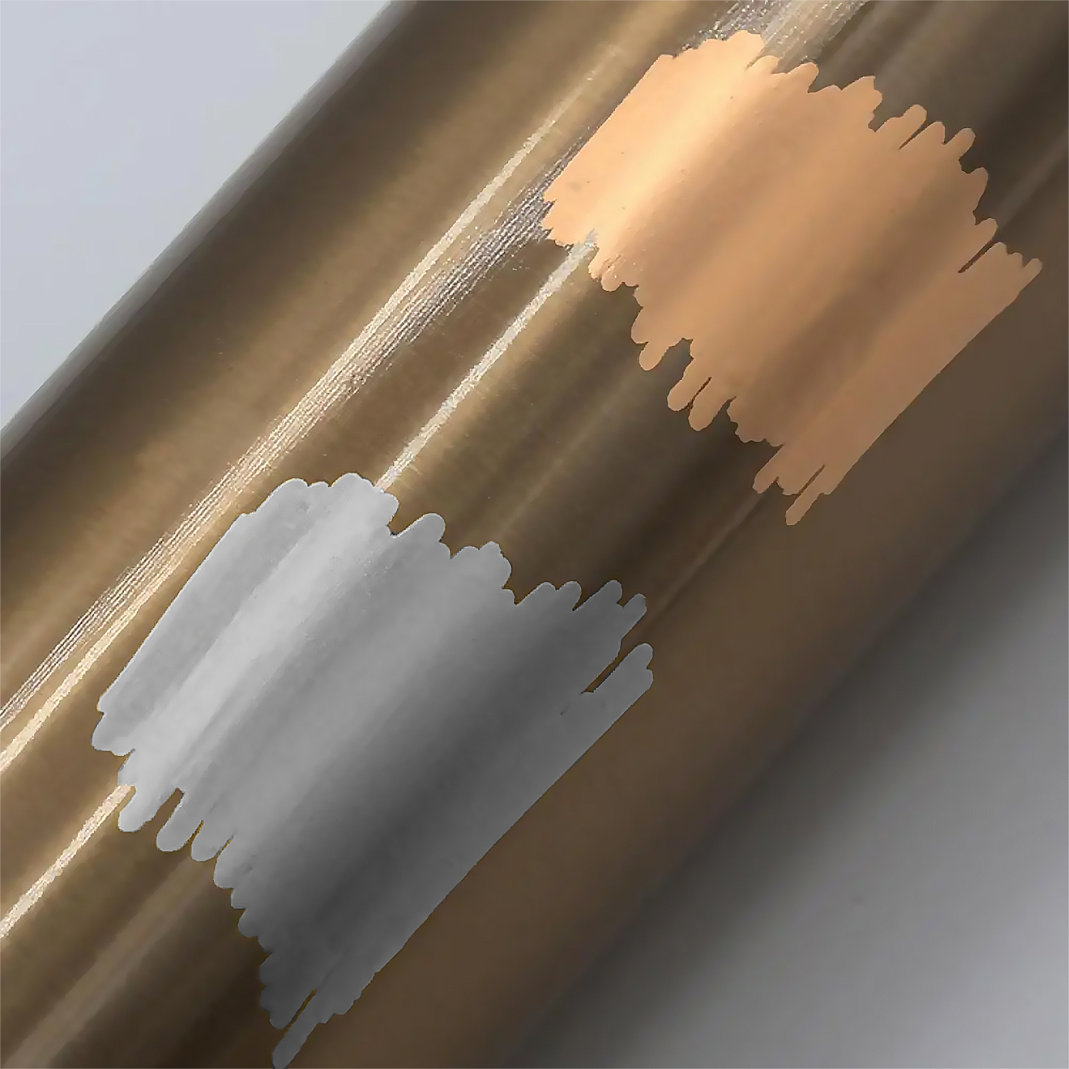 Primer plano de una superficie marrón metálico con pinceladas diagonales en gris claro y melocotón.
