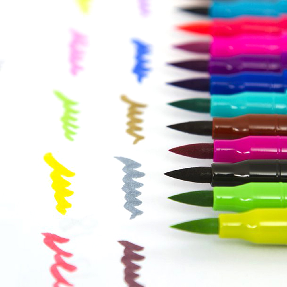 Primer plano de marcadores coloridos con trazos de tinta. Varios colores, incluyendo rosa, azul, verde y amarillo sobre fondo blanco.