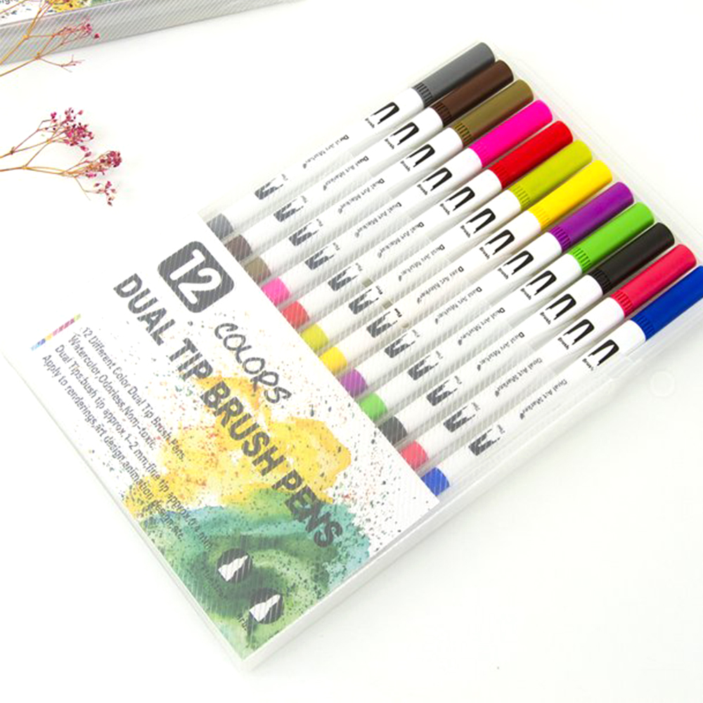 Un juego de 12 rotuladores de doble punta en una funda de plástico transparente. Los rotuladores son de varios colores. La caja dice 'Dual Tip Brush Pens'.