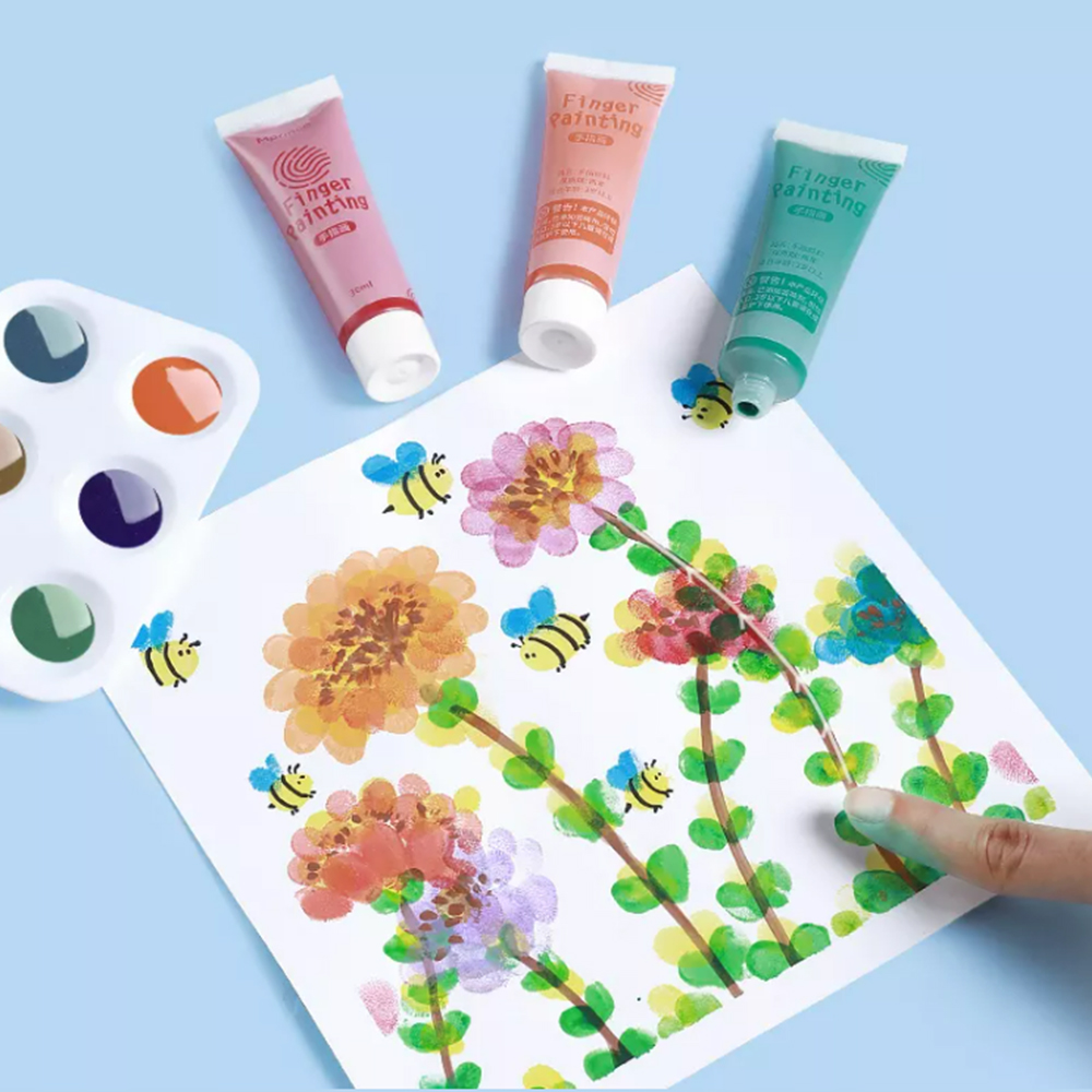Escena de pintura con los dedos con flores y abejas coloridas. Pinturas y una paleta sobre fondo azul. Una mano pintando.