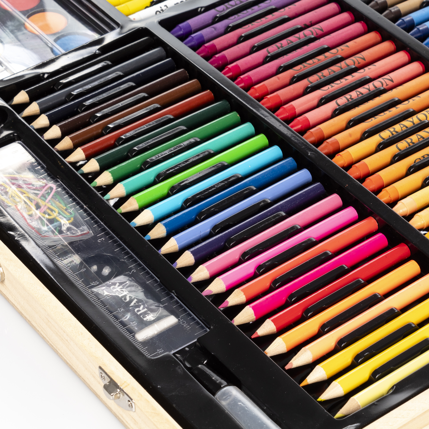 Kit de arte abierto con lápices, crayones y acuarelas. Los lápices son de varios colores. Se ven divisores negros y una regla.