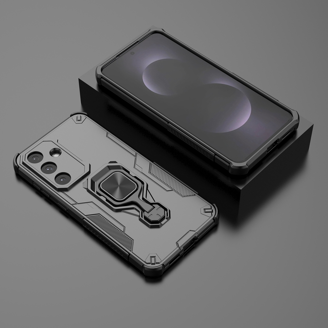 Twee zwarte smartphones met beschermhoesjes. Eén ligt op een zwart blok. Hoesjes hebben ringhouders en camera-uitsparingen.