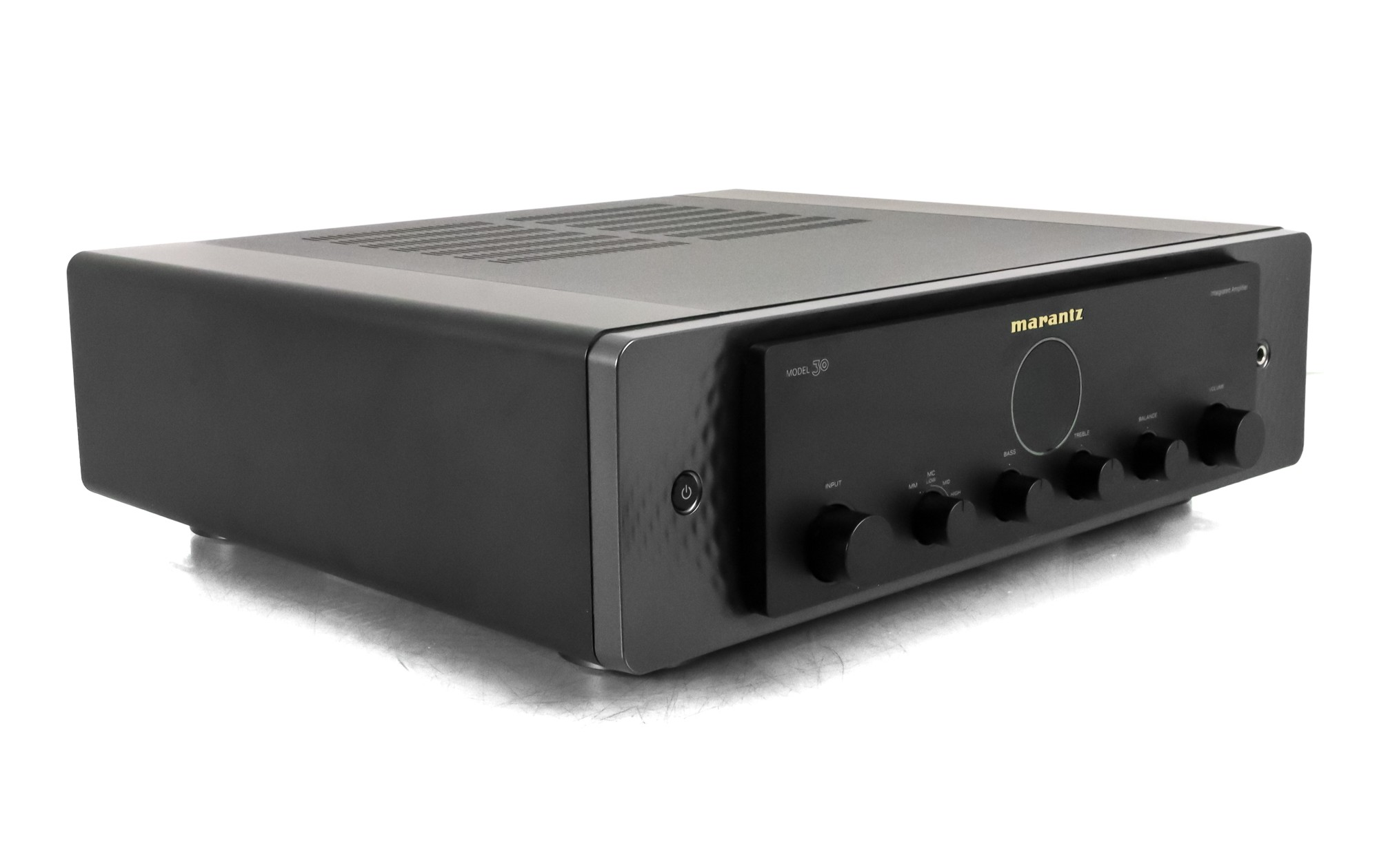 Siyah bir Marantz Model 30 amplifikatör beyaz bir yüzey üzerinde duruyor. Düğmeleri, butonları ve bir güç düğmesi var. Marka adı görünür.