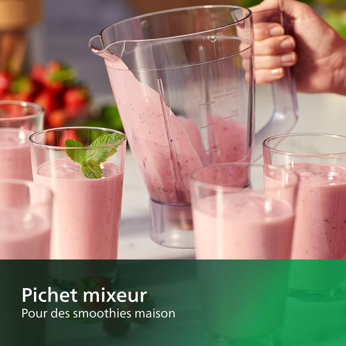 Blender wlewa różowe smoothie do szklanek. Garnish z miętą. Truskawki w tle. Biały stół.