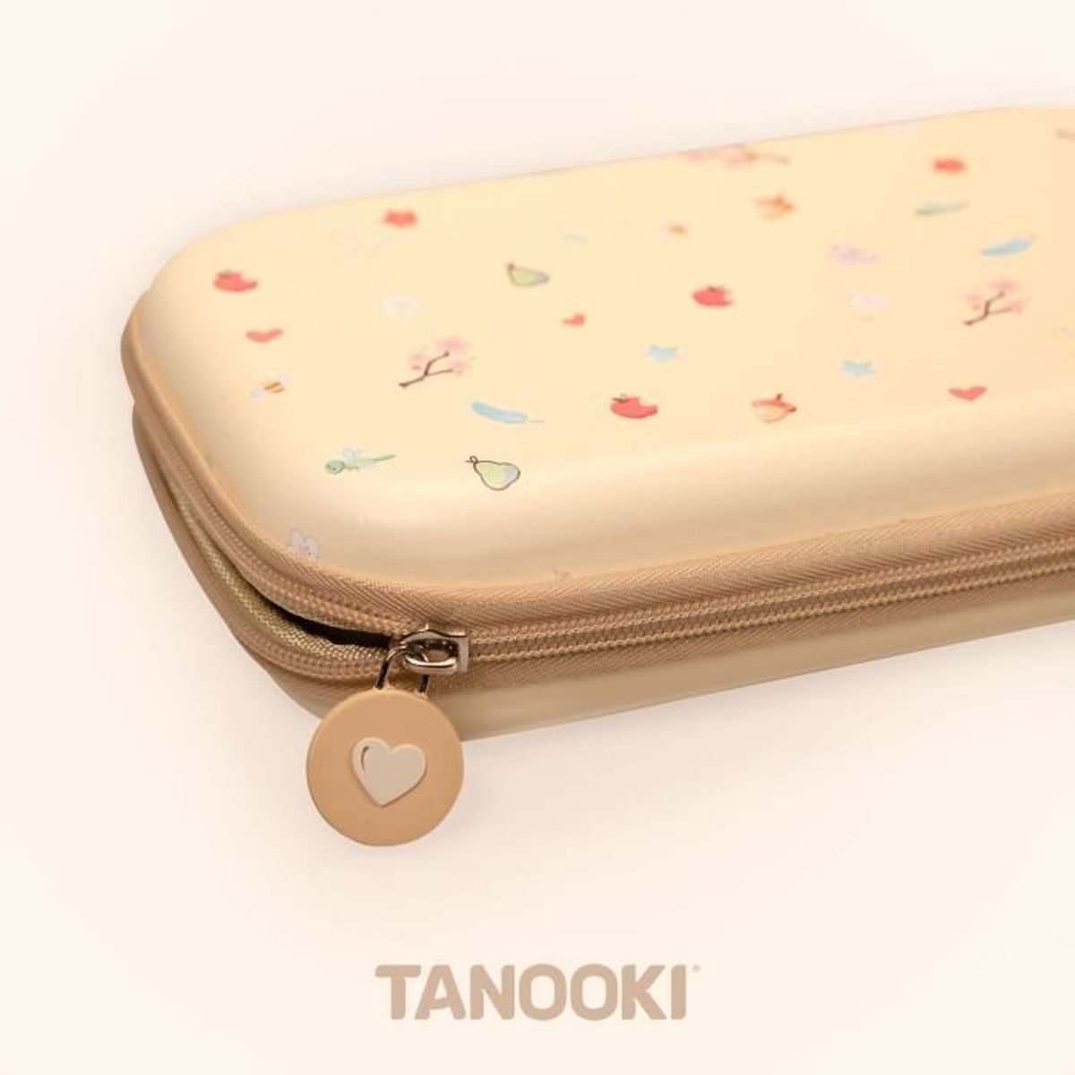 Un estuche beige con patrones florales y una cremallera. El tirador de la cremallera tiene un corazón. La marca 'TANOOKI' es visible.