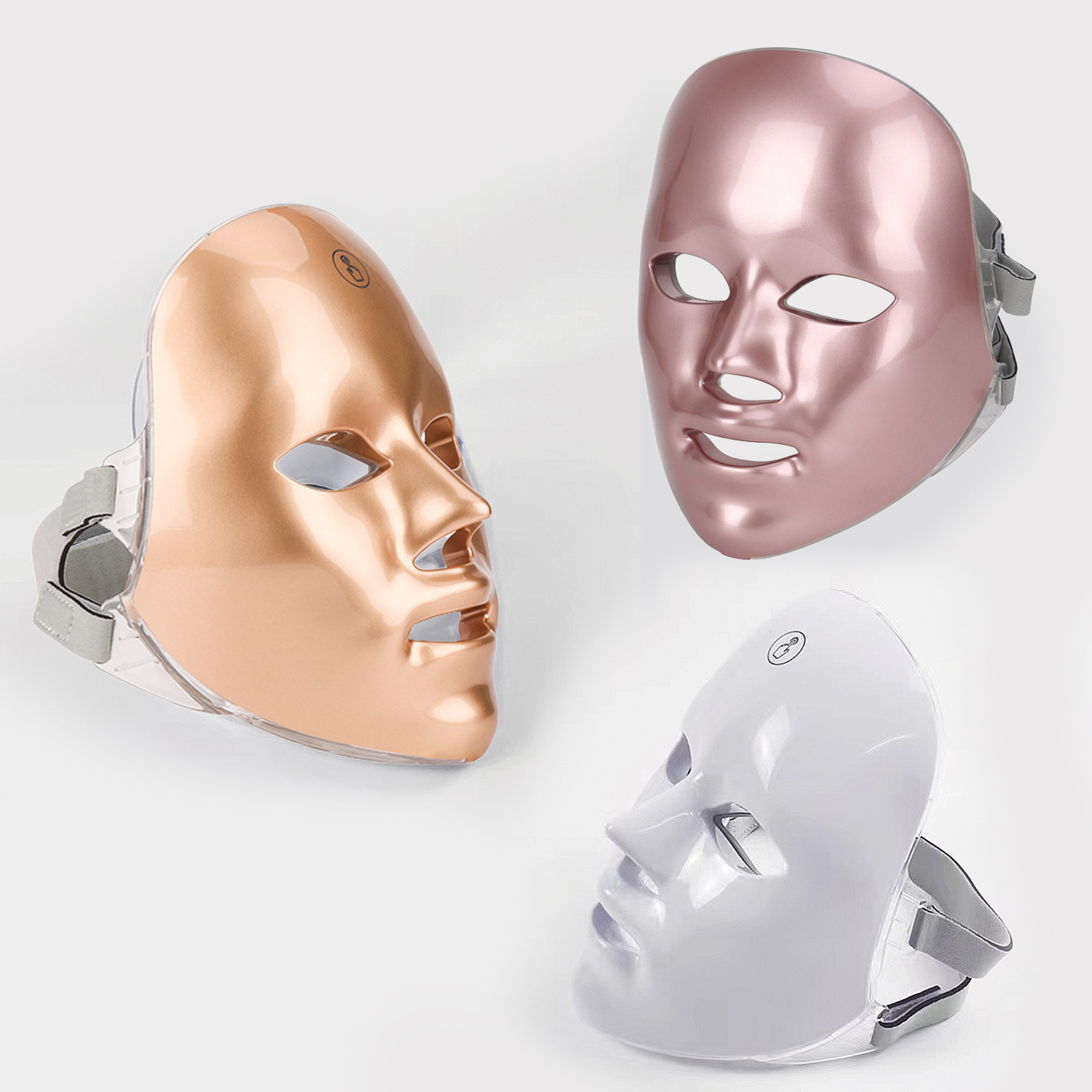 Drei LED-Gesichtsmasken in Rosé, Kupfer und Weiß. Jede hat Augen-, Nasen- und Mundöffnungen mit verstellbaren Riemen auf weißem Hintergrund.