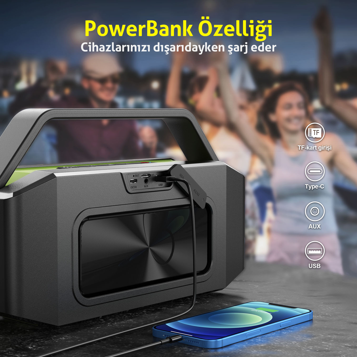 Siyah bir hoparlör, mavi bir telefonu şarj ediyor. İnsanlar arka planda bulanık. Metin PowerBank özelliği ve USB, AUX gibi özellikleri söylüyor.