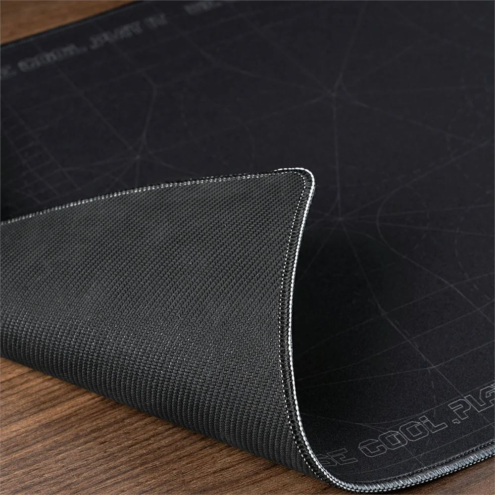 Siyah bir oyun mousepad'inin yakın çekimi. Pad, kenarında beyaz dikişlerle dokulu bir yüzeye sahiptir. Arka plan ahşap bir yüzeydir.