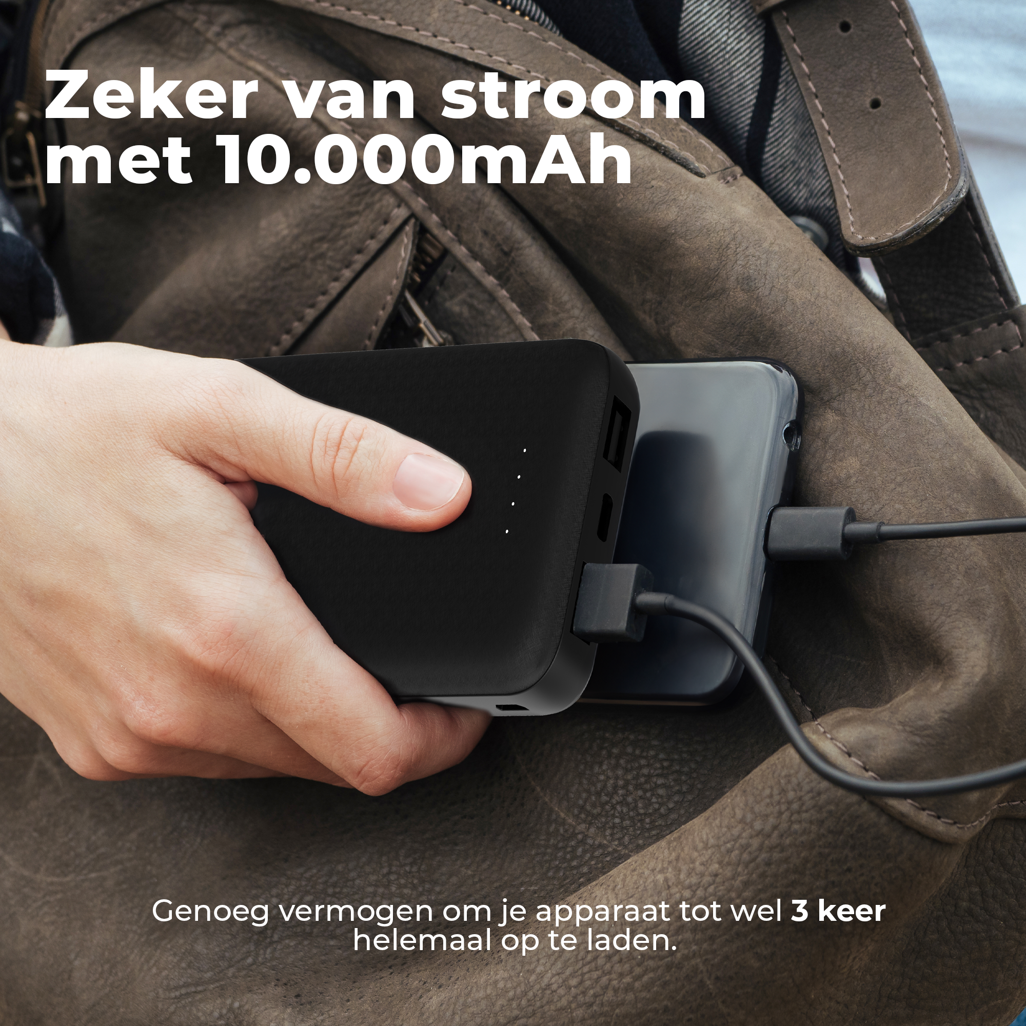 Een hand houdt een zwarte powerbank vast die een telefoon oplaadt. De Nederlandse tekst zegt '10.000mAh' en 'tot 3 keer opladen'.
