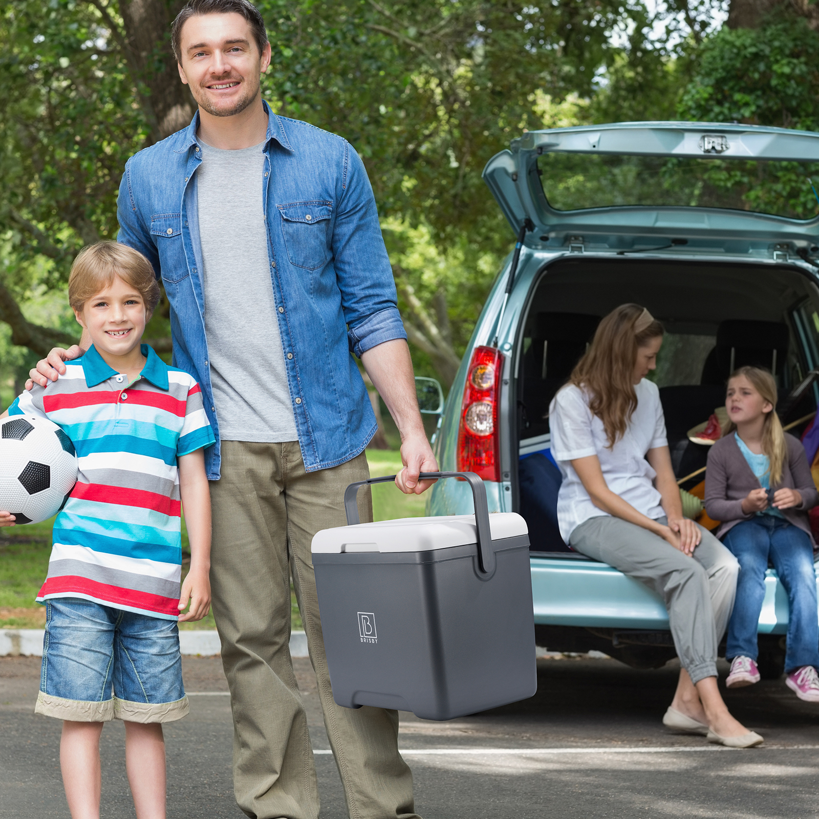 Een familie maakt zich klaar voor een picknick. Een man en een jongen staan met een koelbox en een voetbal.