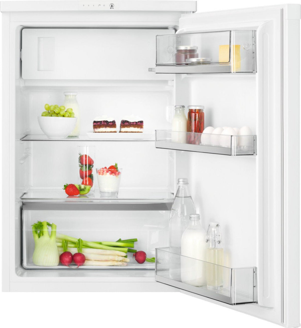 Open refrigerator filled with food: fruits, cakes, eggs, vegetables, jars and bottles. White interior and door.