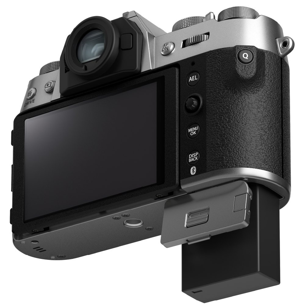 Una fotocamera digitale argentata e nera. Lo schermo LCD è nero. Lo scomparto della batteria è aperto, rivelando una batteria nera.