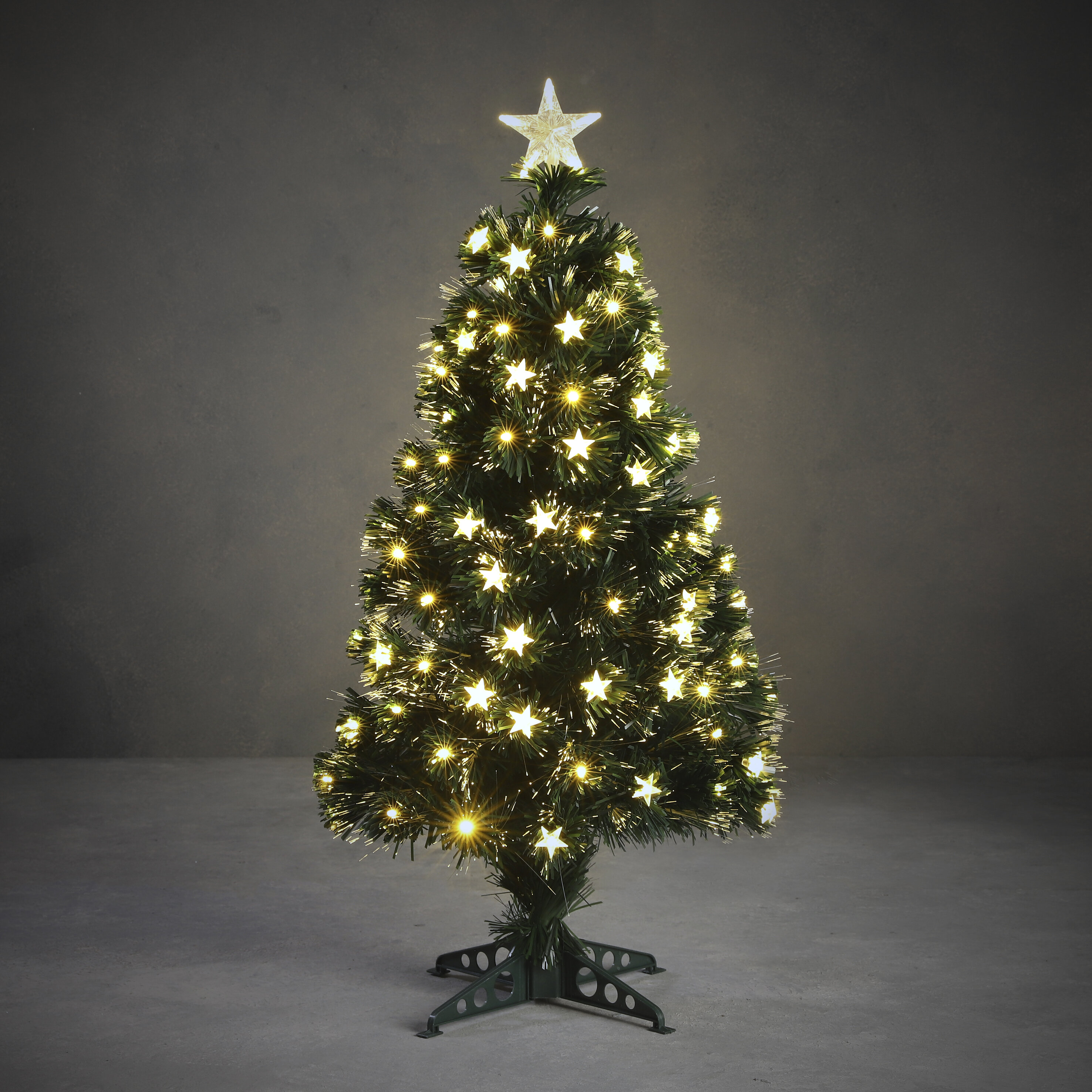 Un petit sapin de Noël avec des lumières en forme d'étoile et une étoile au sommet, sur fond gris.