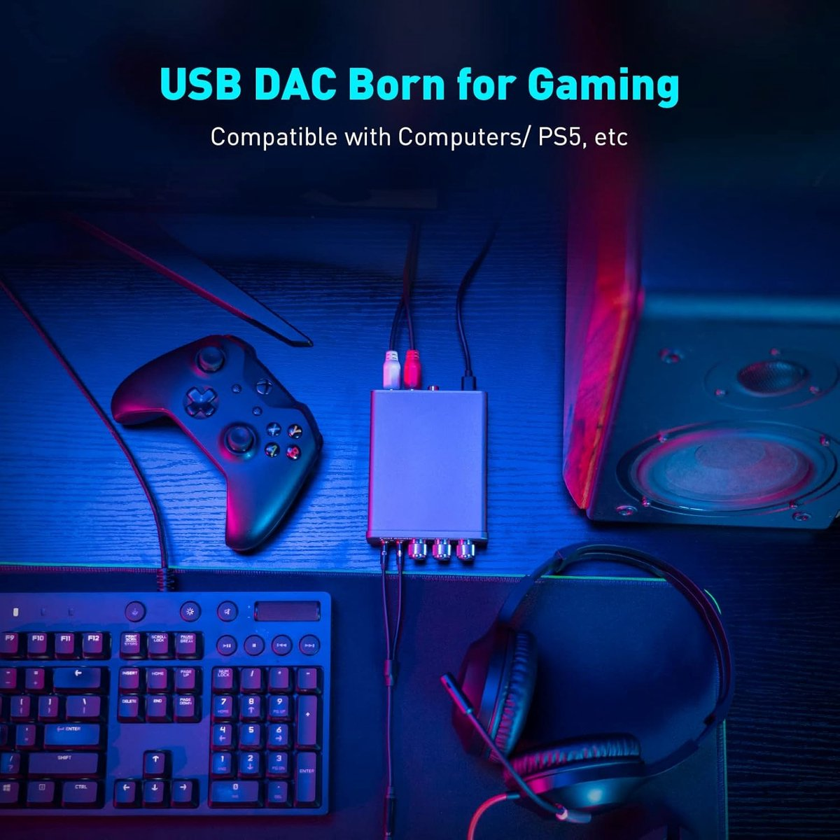 Une configuration de jeu avec une manette, un clavier, un casque, un haut-parleur et un DAC USB. La scène est éclairée en bleu et rose.