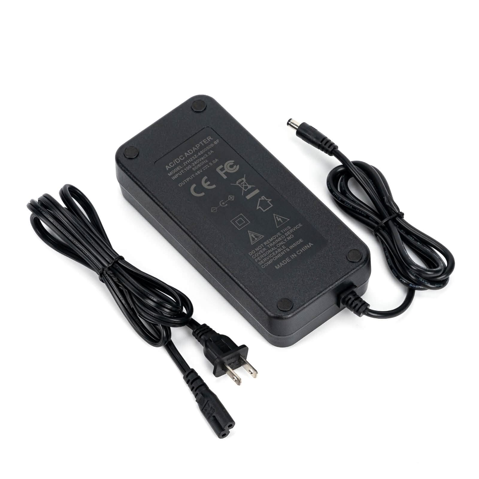 Un adaptateur AC/DC noir avec des câbles et une prise, posé sur un fond blanc.