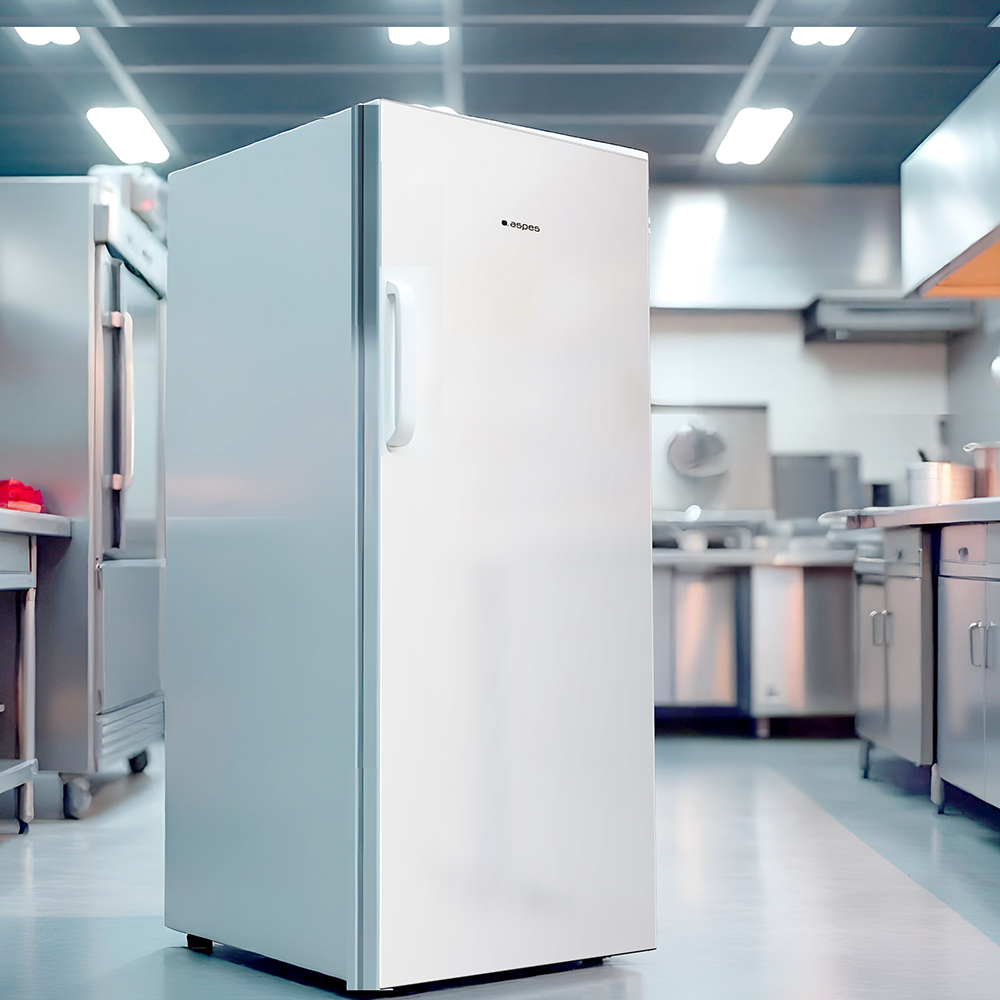 Un refrigerador blanco se encuentra en una cocina. En el fondo se ven otros electrodomésticos y mostradores de acero inoxidable.