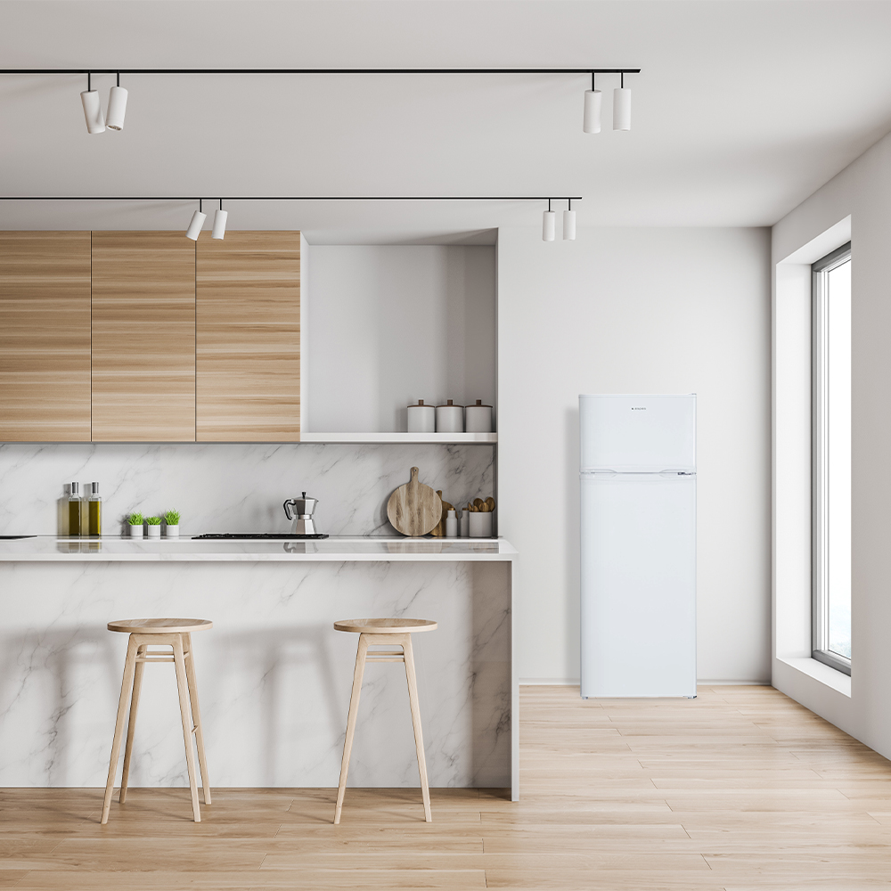 Una cocina moderna con encimera de mármol blanco y armarios de madera. Una nevera blanca está cerca, junto con dos taburetes.