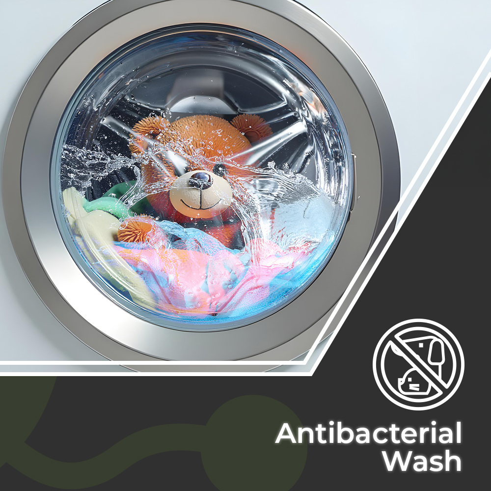 Un oso de peluche y ropa se lavan en una lavadora con agua salpicando. El texto dice lavado antibacteriano.