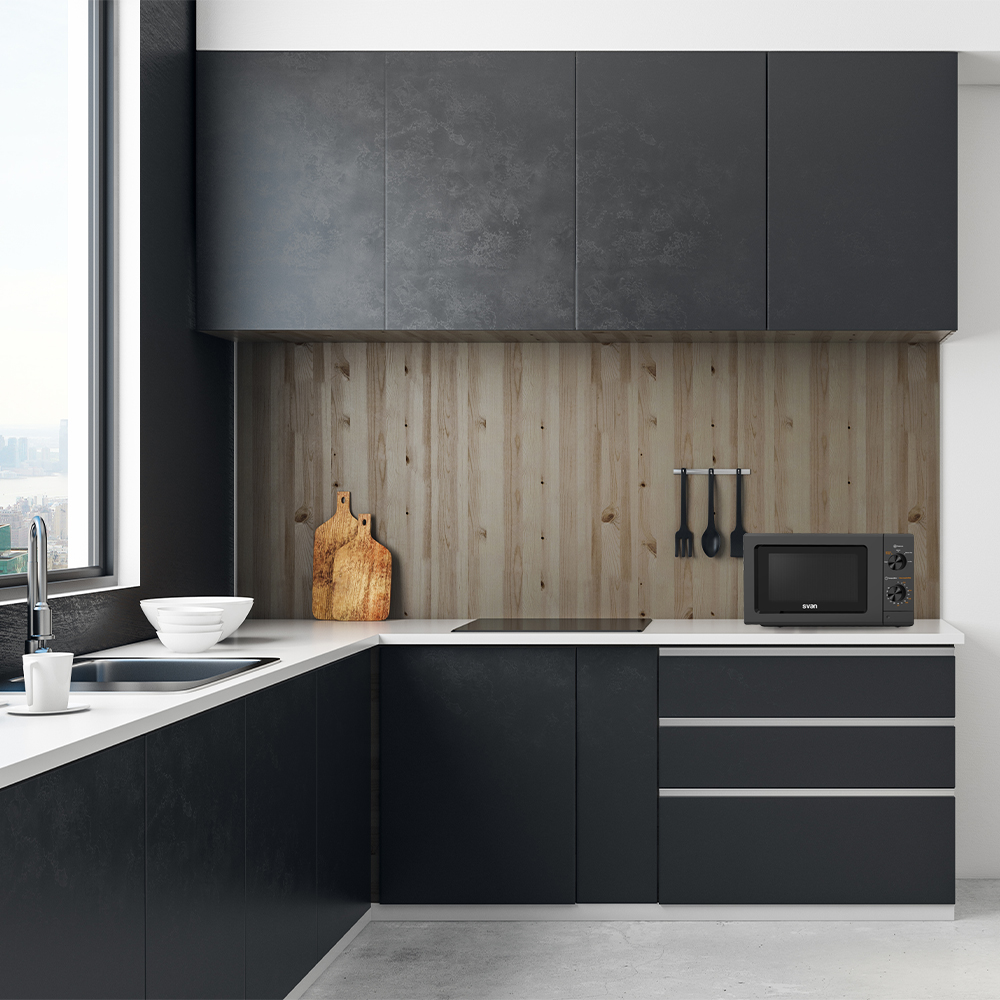 Cocina moderna con gabinetes negros, encimeras blancas y salpicadero de madera. Incluye microondas, tablas de cortar y utensilios.