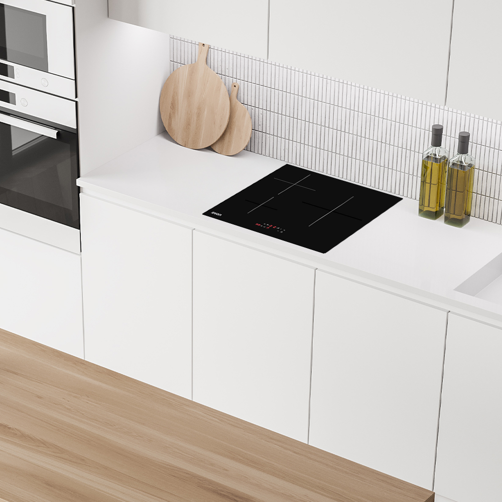 Cocina moderna con vitrocerámica negra, tablas de cortar de madera y botellas de aceite de oliva.