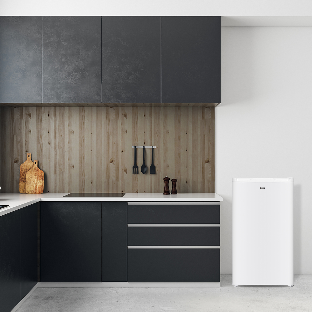 Una cocina moderna con gabinetes oscuros, salpicadero de madera y un refrigerador blanco. Utensilios de cocina colgados.