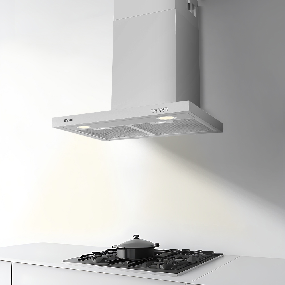 Escena de cocina con campana extractora plateada sobre una encimera negra con una olla, todo contra una pared y encimera blancas.