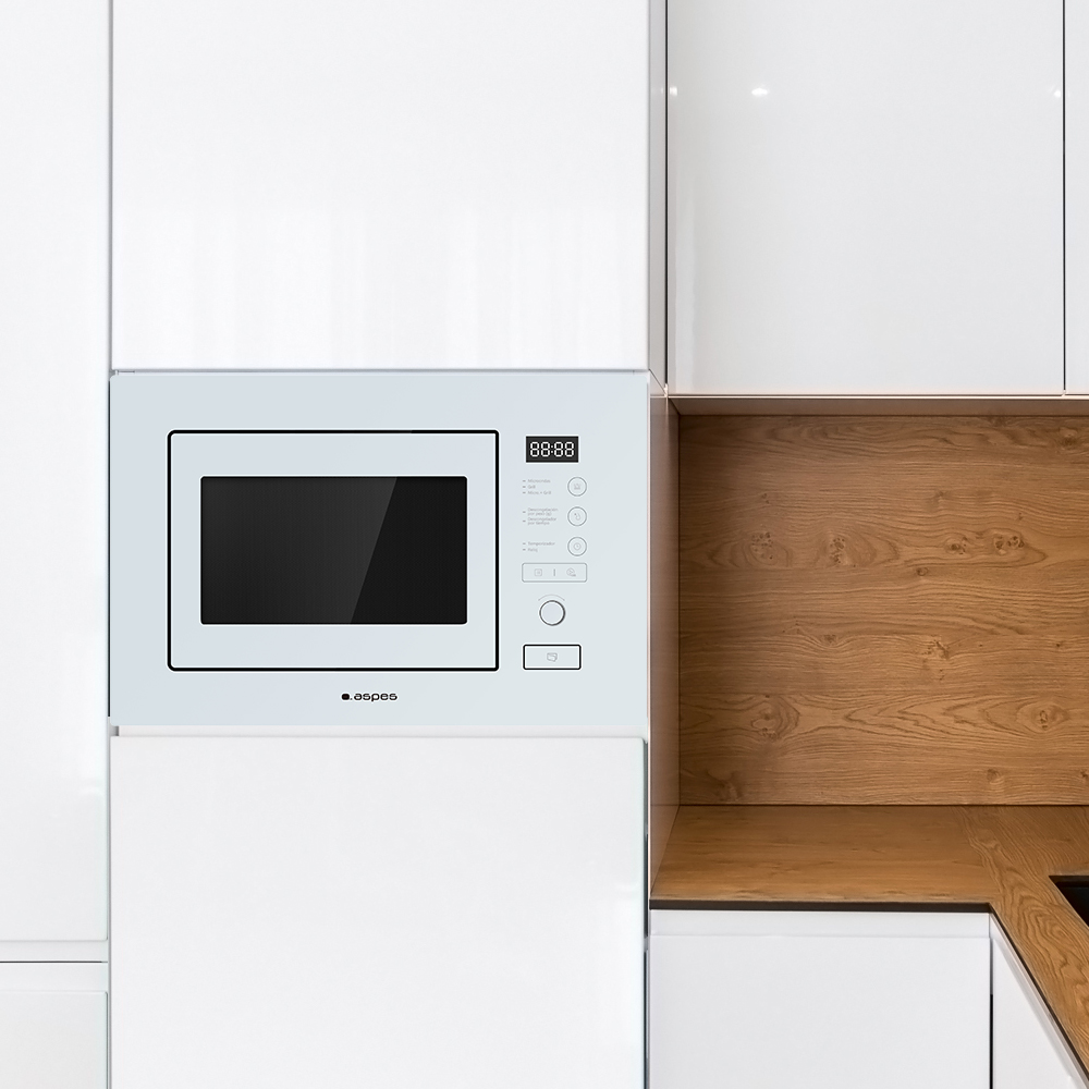 Biała kuchenka mikrofalowa wbudowana w białe szafki. Drewniany panel po prawej stronie. Wyświetlacz pokazuje 88:88.