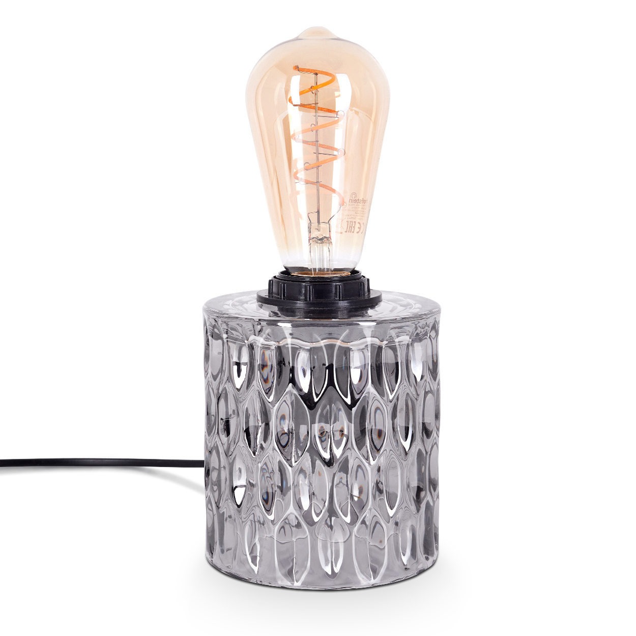 Eine dekorative Lampe mit einem klaren, gemusterten Sockel und einer warm leuchtenden Glühbirne auf weißem Hintergrund.