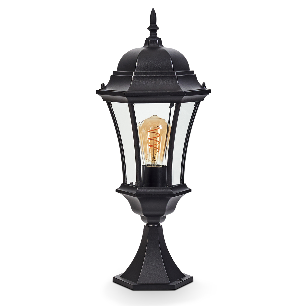 Eine schwarze Außenlampe mit Glasgehäuse. Sie hat eine dekorative Oberseite und eine Edison-Glühbirne im Inneren. Die Lampe steht auf weißem Grund.